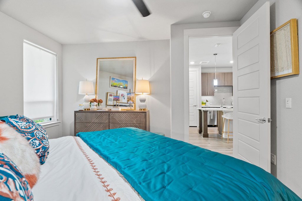 A bedroom with a bed, a dresser, a mirror, and a ceiling fan.