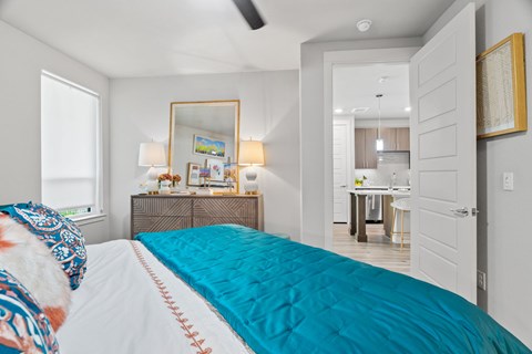 A bedroom with a bed, a dresser, a mirror, and a ceiling fan.