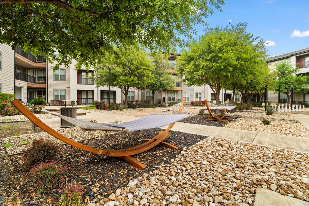 A hammock is strung between two trees in a courtyard.