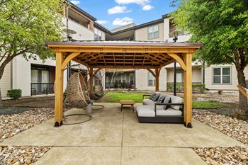 A patio with a wooden pergola and a grey couch.