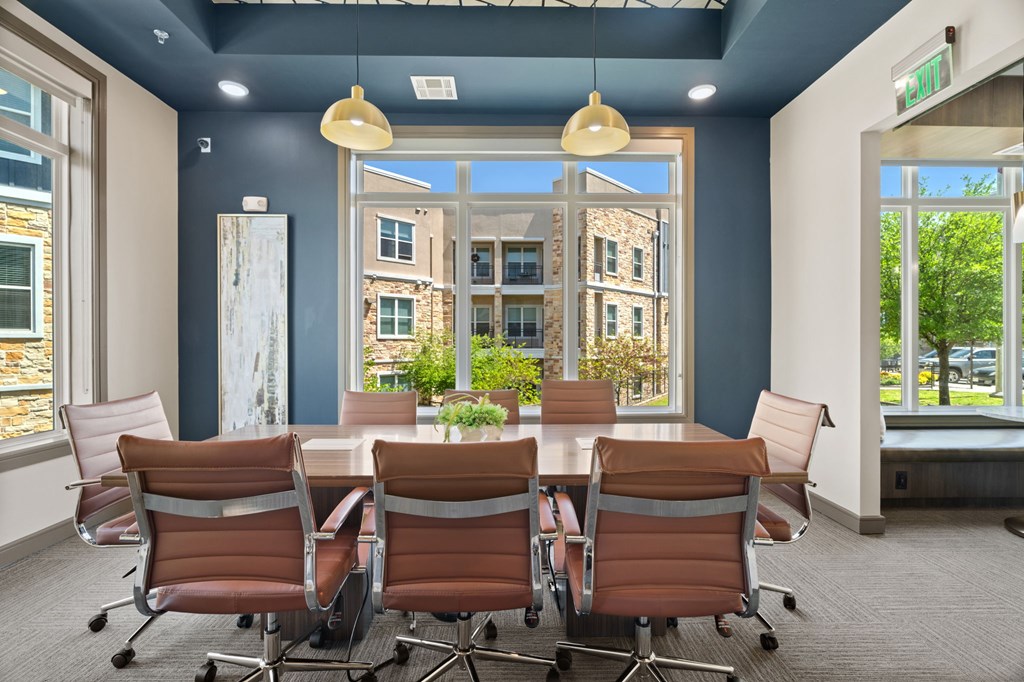 A conference room with a table and chairs and a view of a building outside the window.
