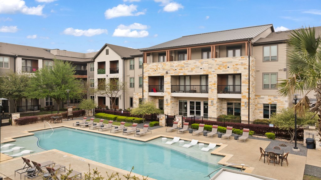 A large apartment complex with a swimming pool in the foreground.