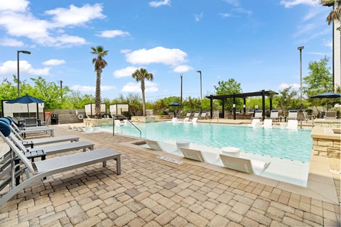 A pool area with sun loungers and palm trees.