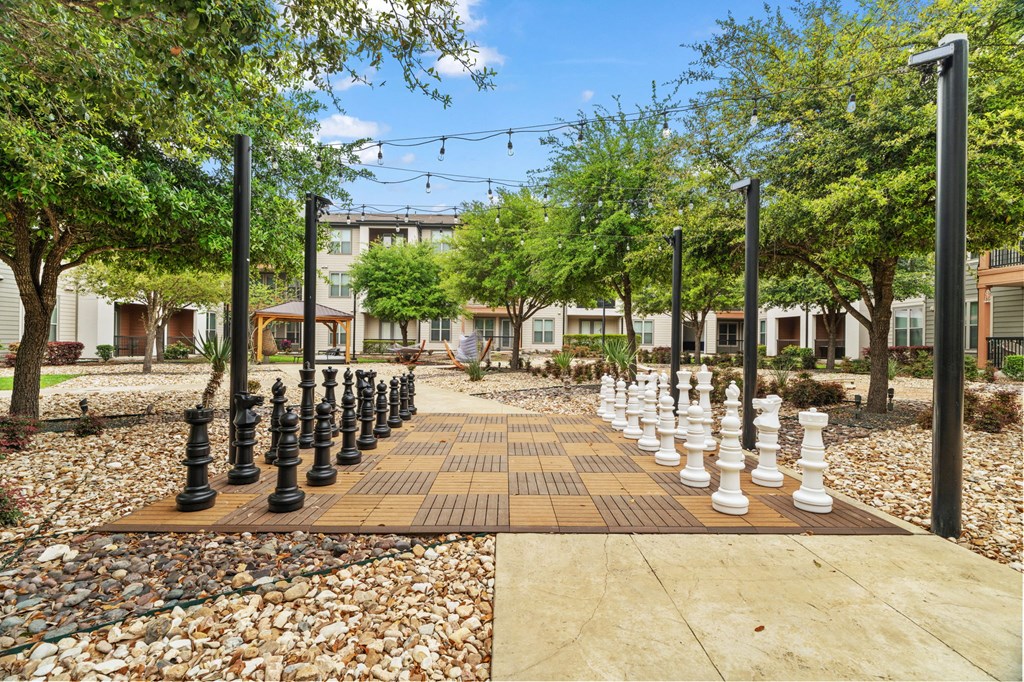 A chess board with black and white pieces in the middle of a walkway.