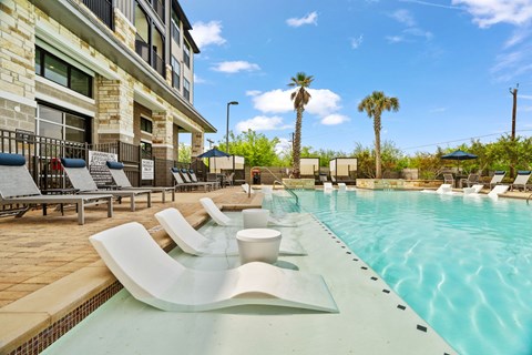 A pool with a white bench and a building behind it.