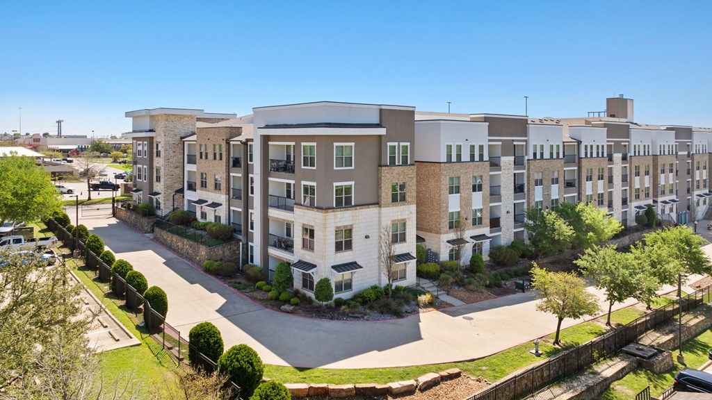 A large apartment complex with a parking lot in front.
