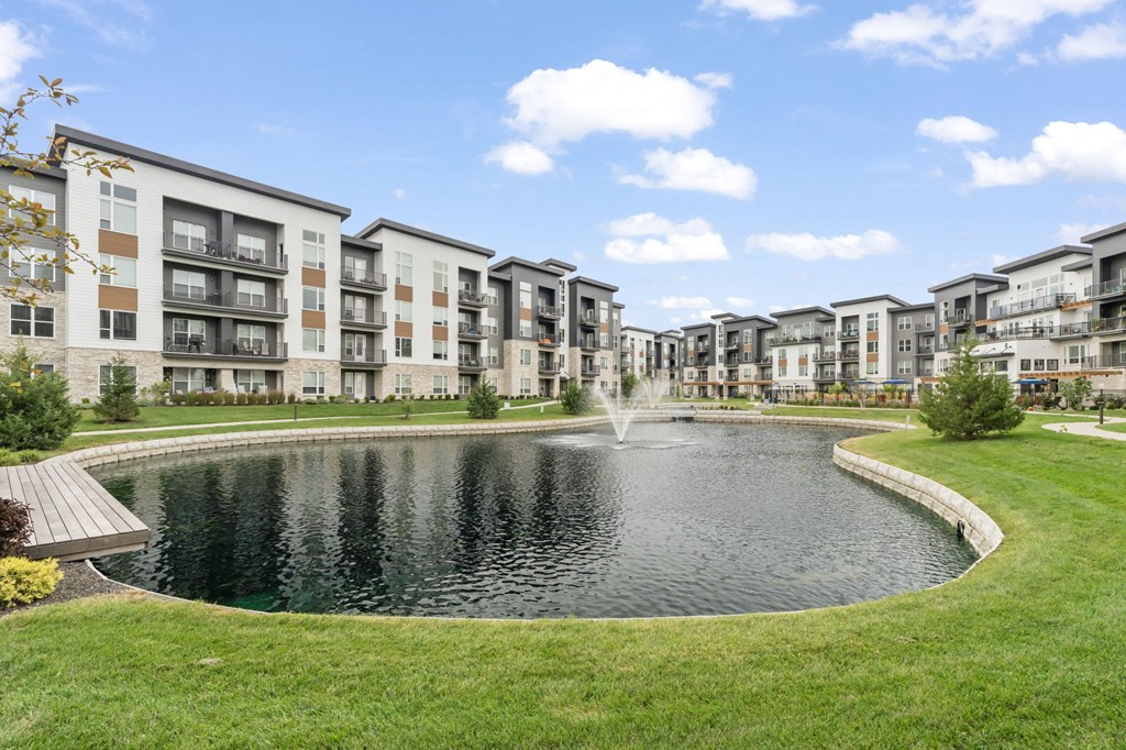 a pond with a fountain in the middle of an apartment complex