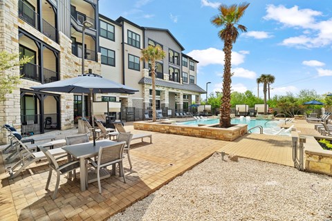 A pool area with a table and chairs and a palm tree.
