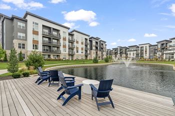 an outdoor patio with blue chairs and a pond with a fountain