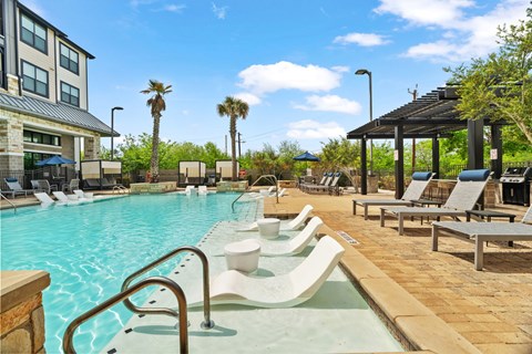 A pool with a slide and sun loungers.