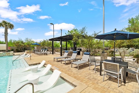 A pool area with sun loungers and a barbecue grill.