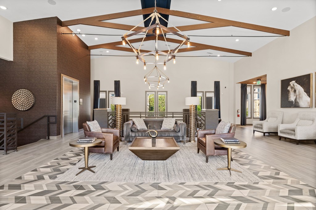 A large, open living room with a wooden floor and a chandelier hanging from the ceiling.