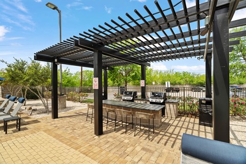 A patio with a bar and chairs under a pergola.