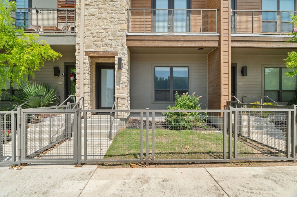A modern two-story apartment building with a metal fence in front.