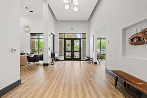 A modern office lobby with a bench, chairs, and a sculpture on the wall.