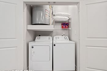 a small laundry room with a washer and dryer and a shelf above the