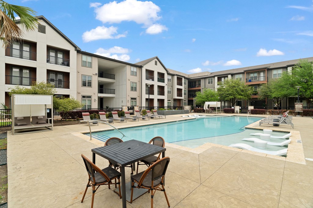 A table and chairs are set up outside a building with a pool.