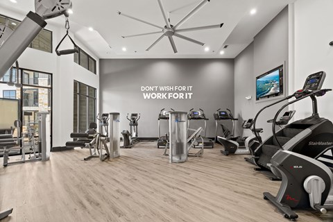 A gym with a variety of equipment and a motivational sign on the wall.