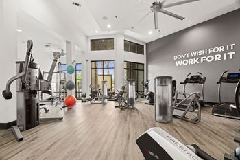 A gym with a variety of equipment and a motivational quote on the wall.