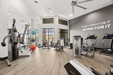 A gym with a variety of equipment and a motivational quote on the wall.