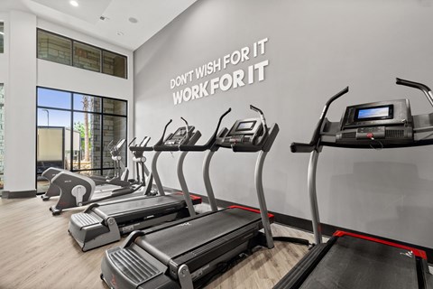 A gym with treadmills and a wall that says "Don't wish for it, work for it".