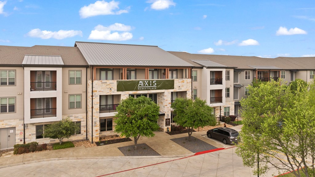 Axis apartments building with a tree in front.