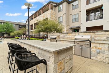 A patio with chairs and a stone wall in front of a building.