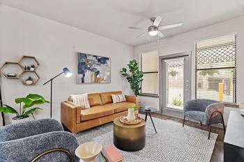 A living room with a couch, chairs, and a ceiling fan.