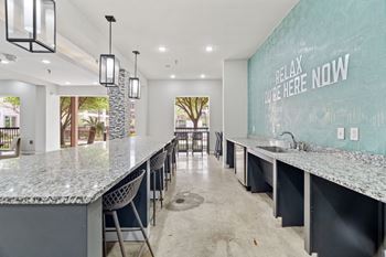 A kitchen with a counter and chairs and a sign on the wall.