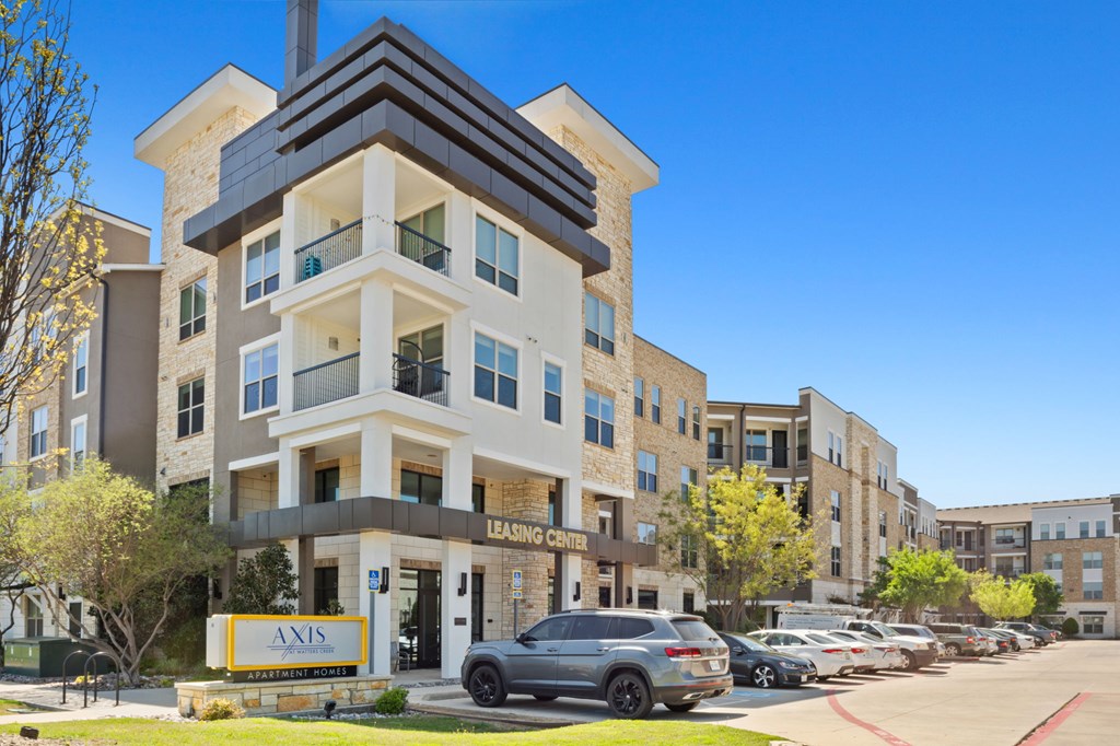 A modern apartment building with a leasing sign in front.