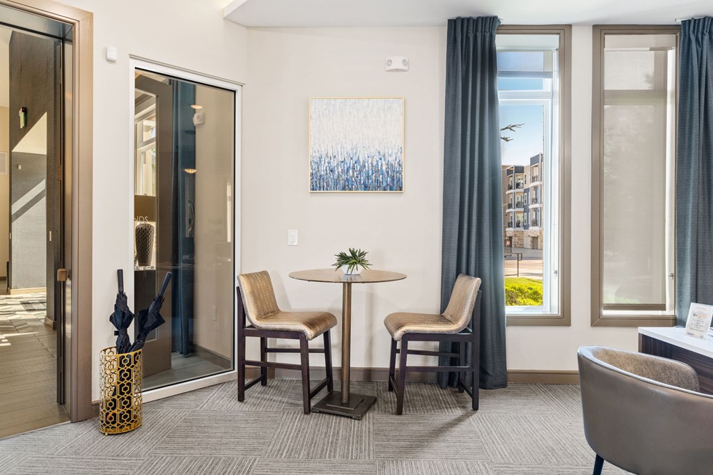 A room with a table and chairs and a painting on the wall.