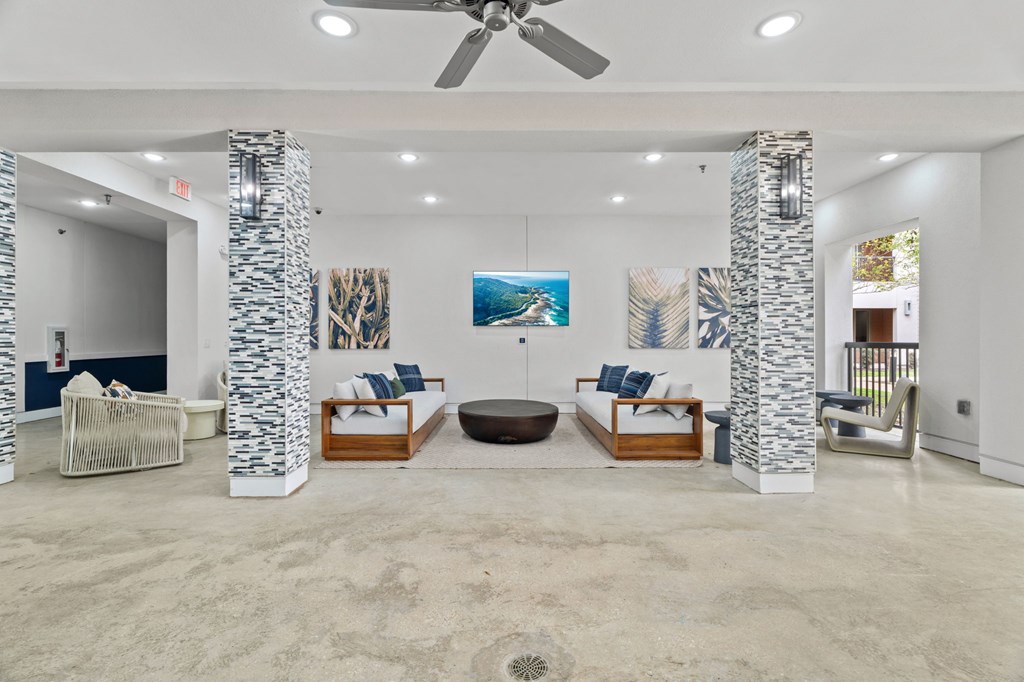 A spacious living room with a ceiling fan and a large painting on the wall.