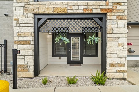 A house entrance with a black gate and a stone wall.