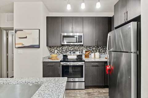 A modern kitchen with a stainless steel refrigerator and a marble countertop.