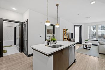 an open kitchen and living room with white walls and wood floors