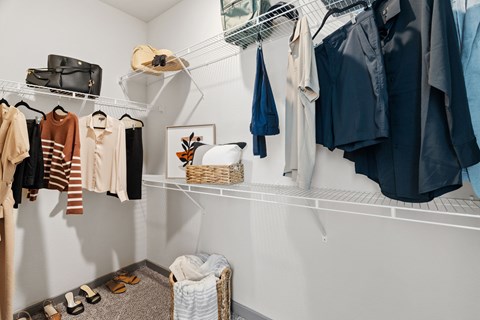 A white closet with clothes and shoes.