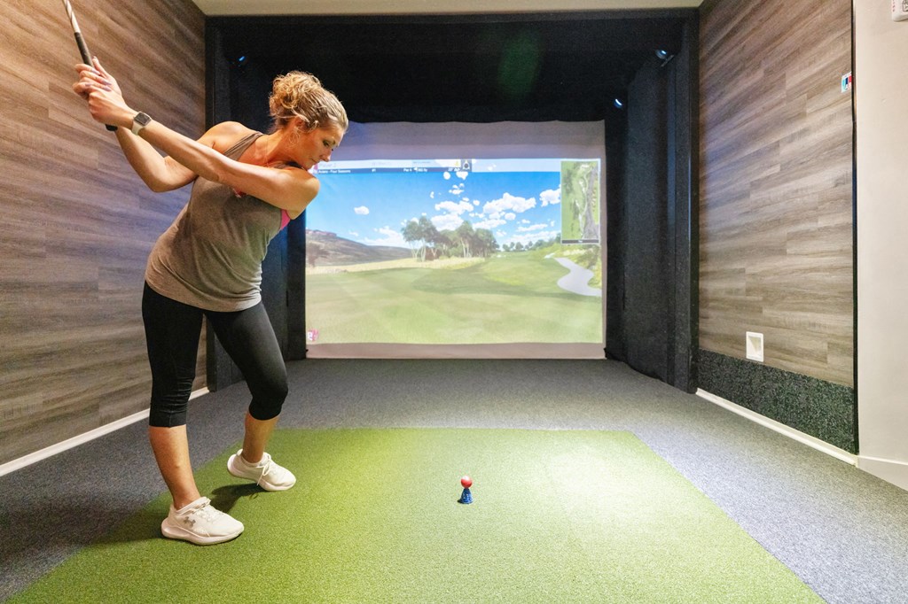 a woman playing a game of golf on a simulator