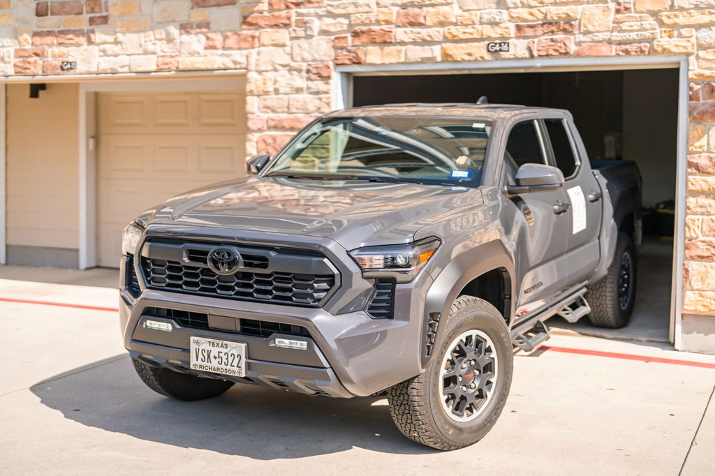 A grey Toyota truck is parked in front of a garage.