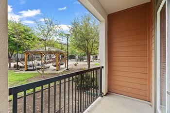 A balcony with a black railing and a view of a playground.