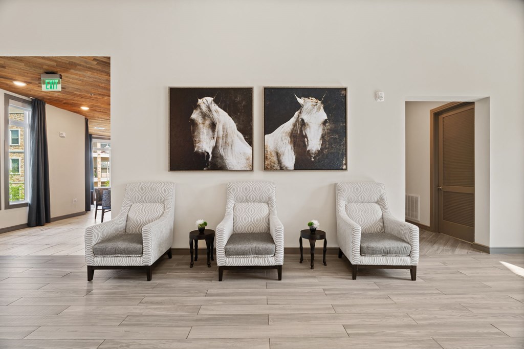 Three chairs are placed in front of two paintings of horses.