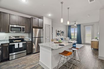 A modern kitchen with dark brown cabinets and stainless steel appliances.
