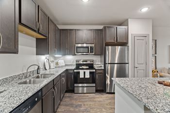 A modern kitchen with dark wood cabinets and stainless steel appliances.