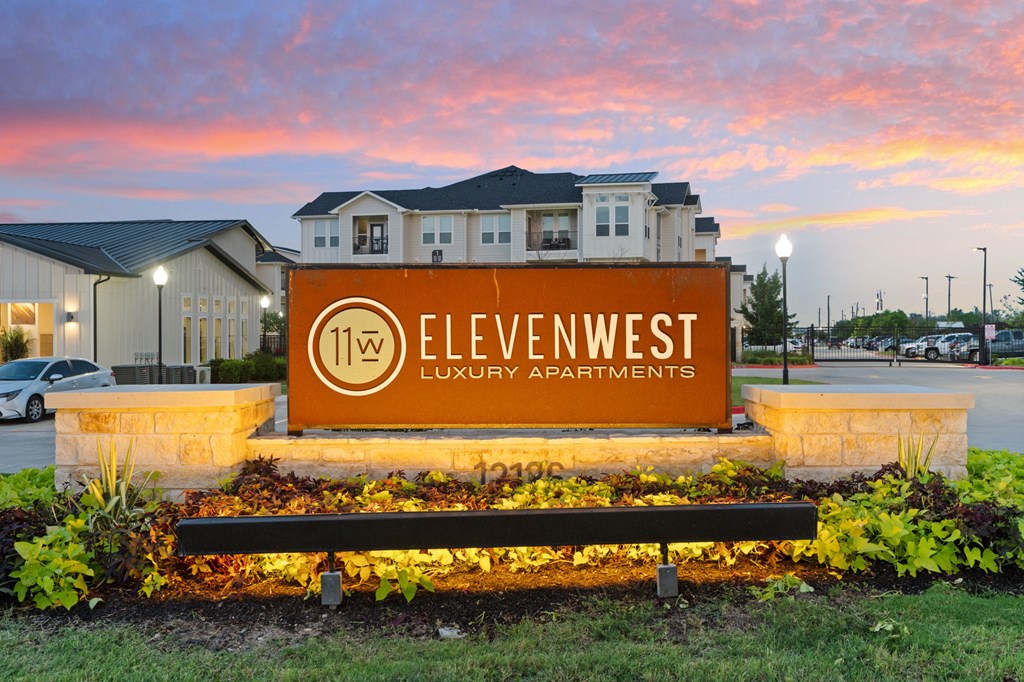 A sign for Elevenwest Luxury Apartments is displayed in front of a building.