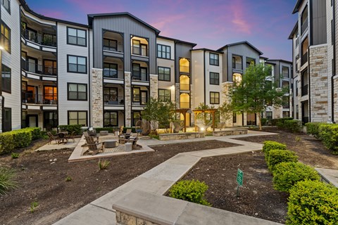 A courtyard surrounded by apartment buildings with a small garden in the middle.