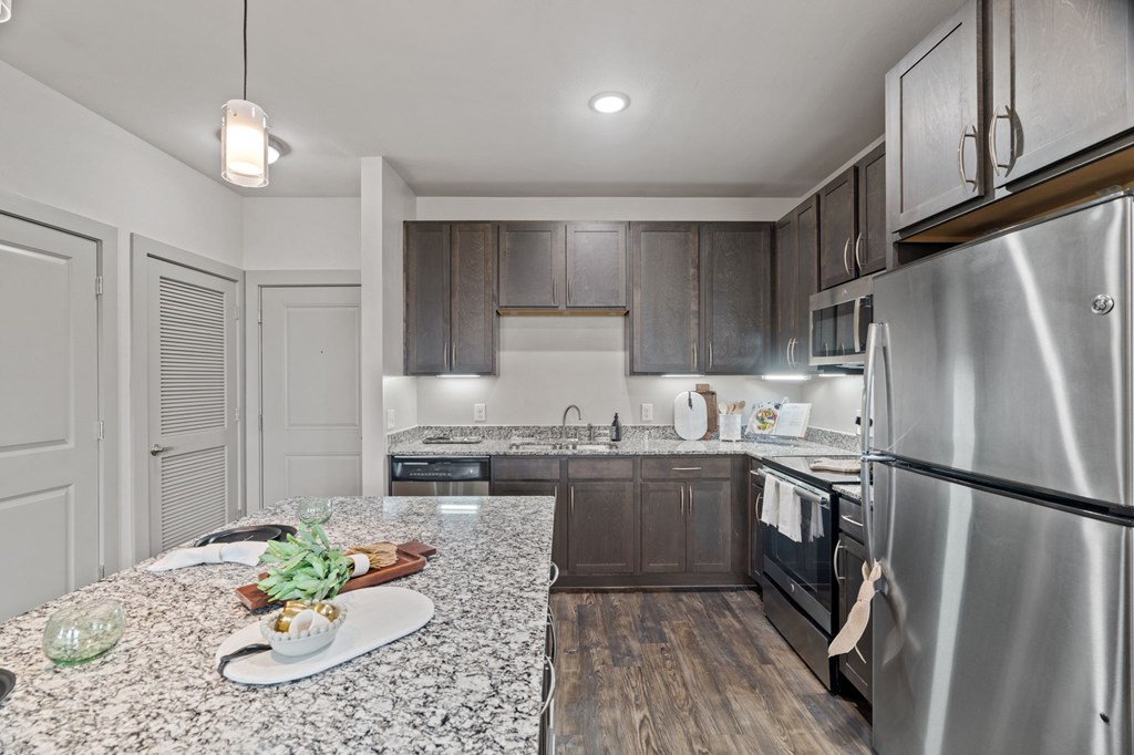 A modern kitchen with a granite countertop and stainless steel appliances.