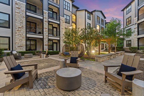 A patio area with a fire pit and seating area in front of apartment buildings.