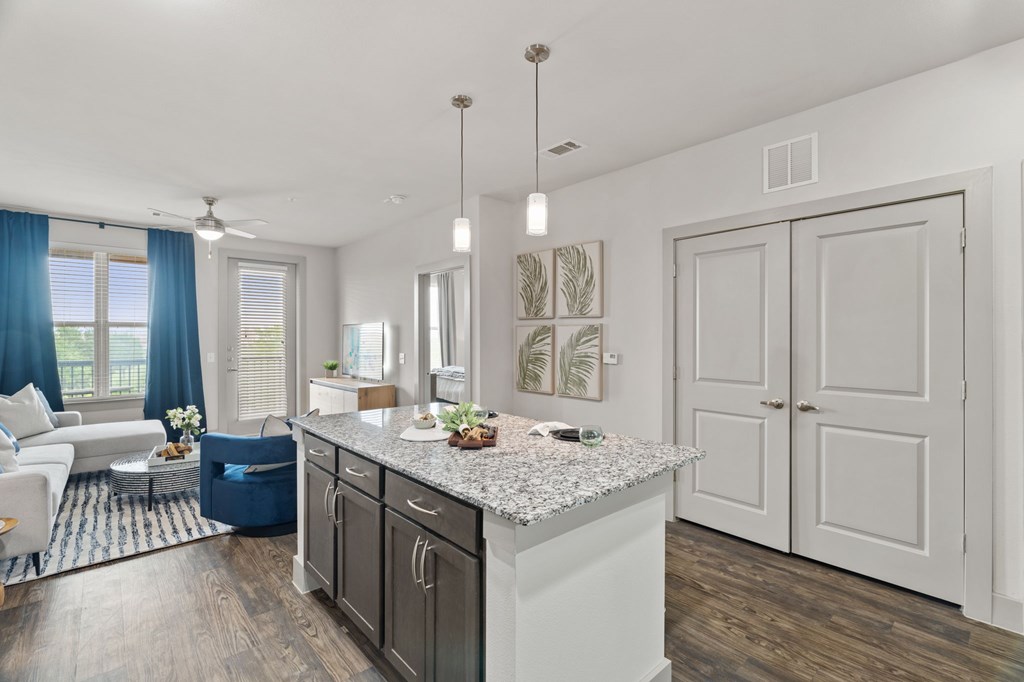A kitchen with a large island and a dining area with a table and chairs.