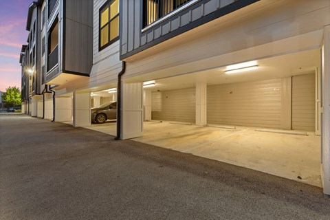 A car is parked in the garage door of a modern building.