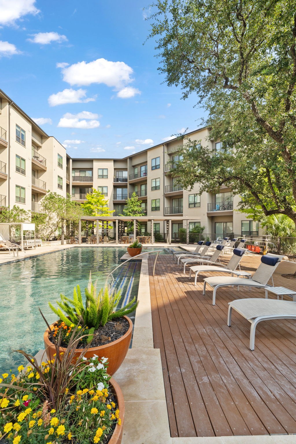 A pool area with chairs and a building in the background.