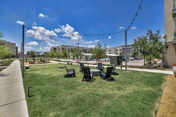 a grassy area with a table and chairs and a building in the background
